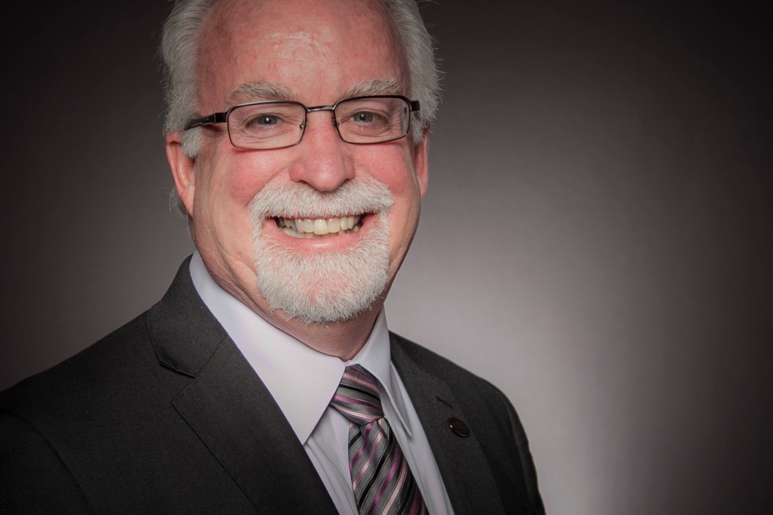 A man with glasses and a beard wearing a suit