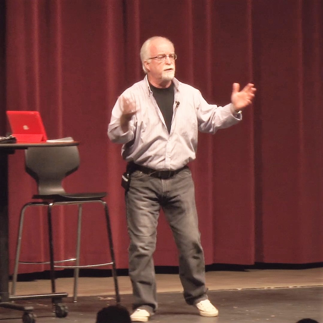 A man standing on stage with his hands raised.