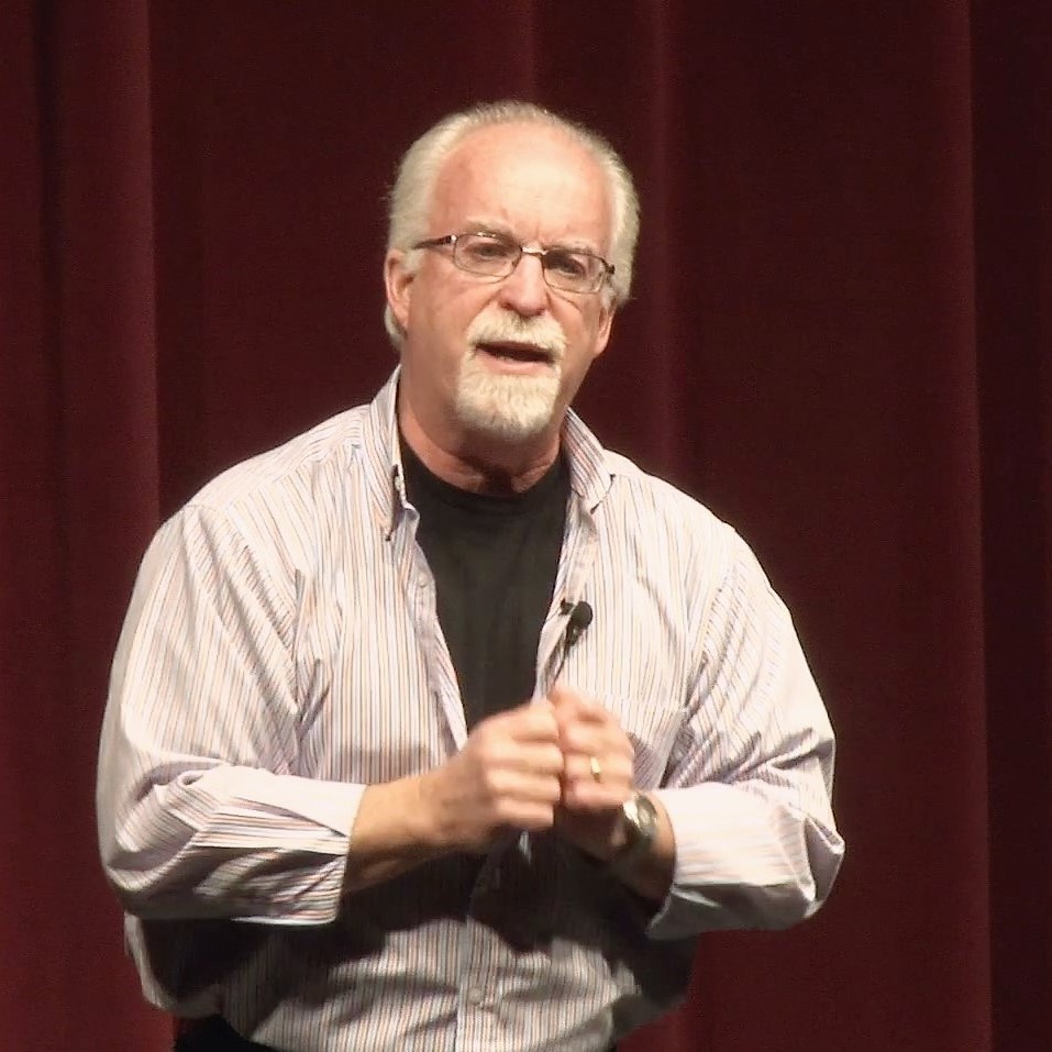 A man with glasses and beard standing on stage.