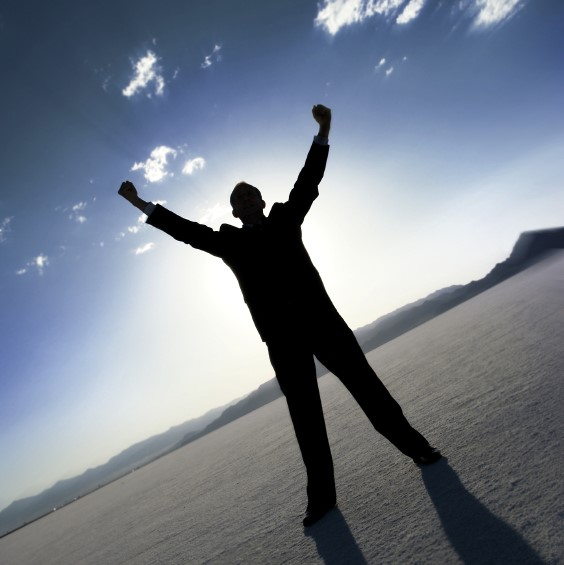 A man standing on the beach with his arms in the air.